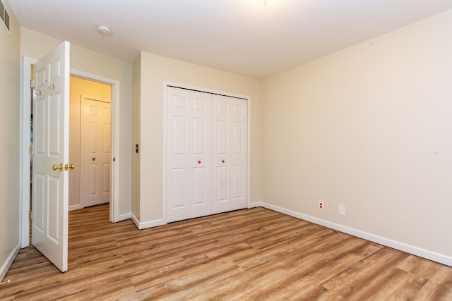 unfurnished bedroom with light wood-style floors, visible vents, baseboards, and a closet