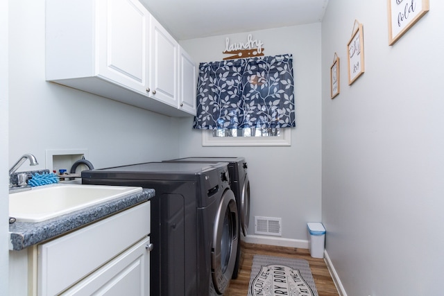 laundry room with wood finished floors, visible vents, baseboards, cabinet space, and washer and clothes dryer