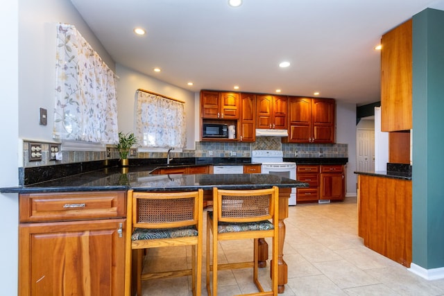 kitchen featuring white appliances, under cabinet range hood, backsplash, and recessed lighting