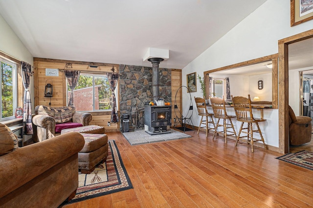 living room featuring lofted ceiling, a wood stove, a healthy amount of sunlight, and hardwood / wood-style floors