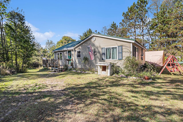 view of front of house with a deck, a front yard, and a playground