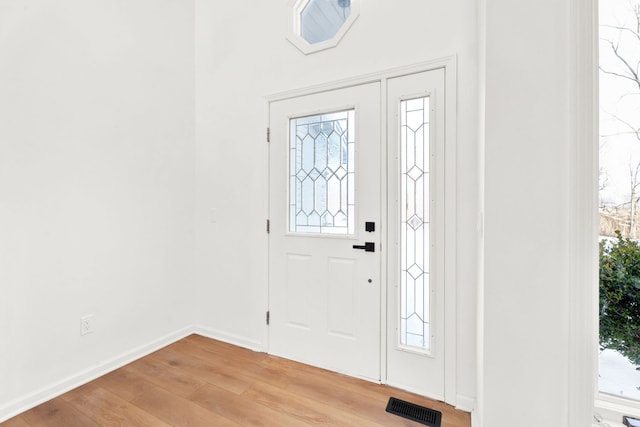 foyer entrance with visible vents, light wood-style flooring, and baseboards