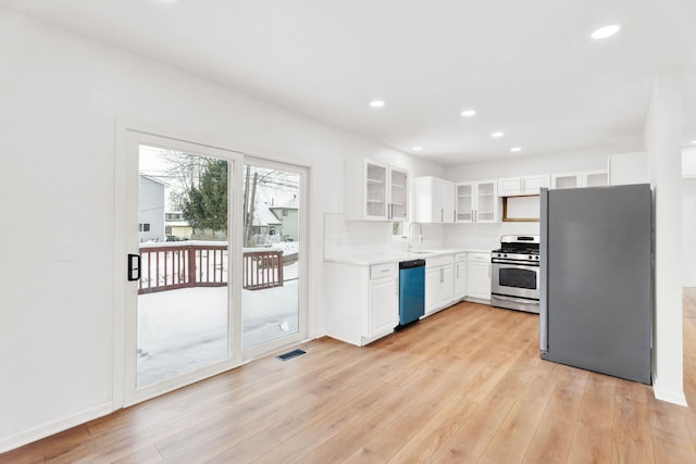 kitchen featuring appliances with stainless steel finishes, white cabinetry, glass insert cabinets, and light wood finished floors