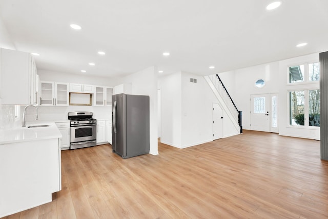 kitchen with light wood finished floors, light countertops, appliances with stainless steel finishes, and a sink