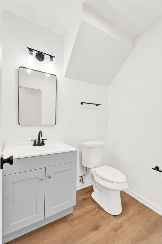 half bathroom featuring vanity, wood finished floors, toilet, and baseboards