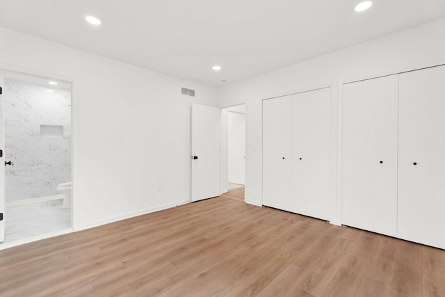 unfurnished bedroom featuring visible vents, connected bathroom, light wood-style floors, two closets, and recessed lighting