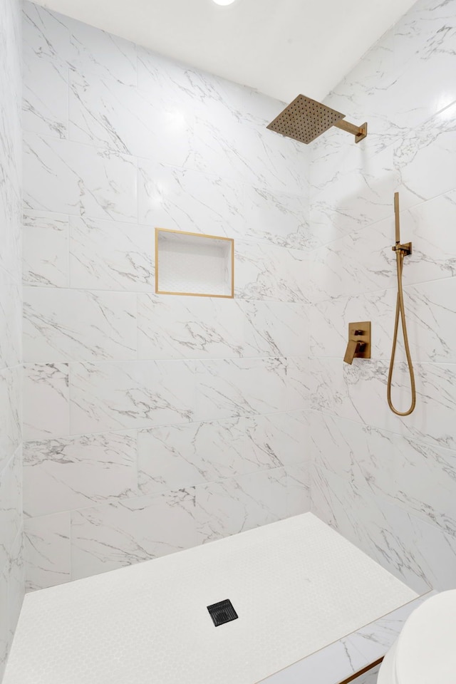 bathroom featuring a marble finish shower and toilet