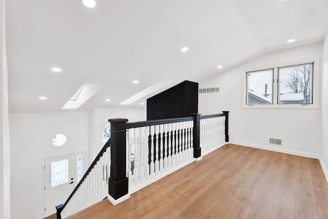 corridor featuring light wood-style flooring, an upstairs landing, and visible vents