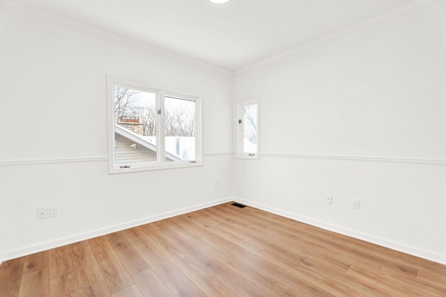 spare room featuring crown molding, light wood-style flooring, and baseboards