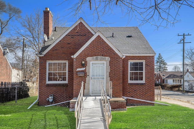 view of front of property with brick siding, a front yard, and fence