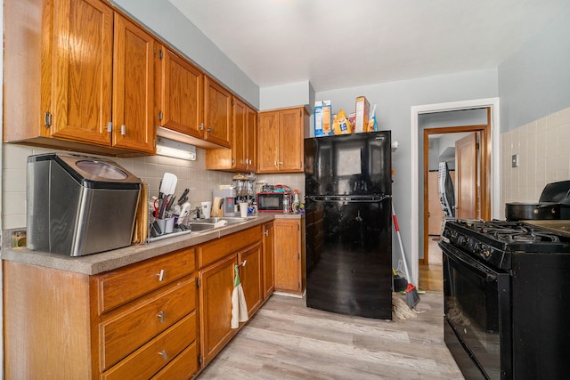 kitchen featuring light wood-style flooring, black appliances, light countertops, brown cabinets, and backsplash