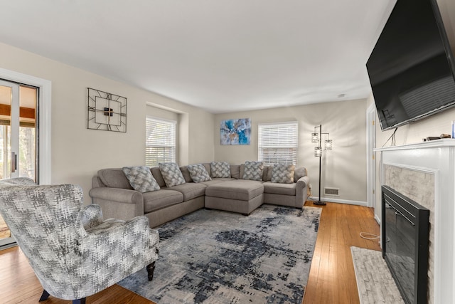 living area featuring light wood-type flooring, baseboards, visible vents, and a tiled fireplace