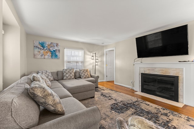 living room featuring a glass covered fireplace, wood finished floors, and baseboards