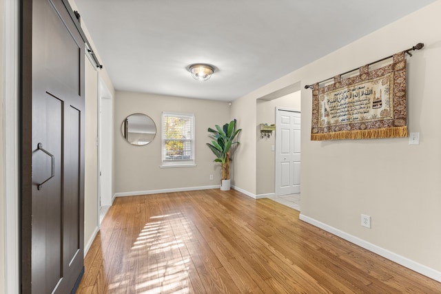 foyer featuring light wood-style floors, baseboards, and a barn door