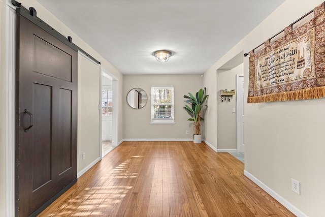 entryway with light wood-style flooring, baseboards, and a barn door