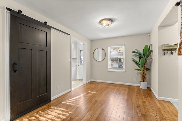 foyer featuring light wood-style floors, a barn door, and baseboards