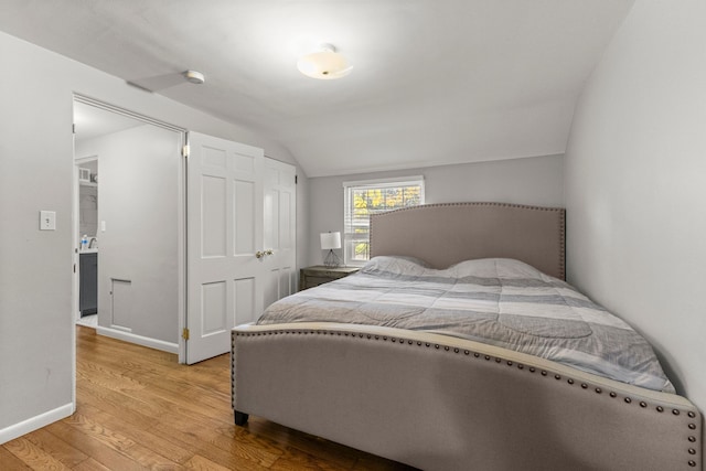 bedroom with light wood-style floors, vaulted ceiling, and baseboards