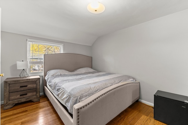 bedroom with vaulted ceiling, hardwood / wood-style floors, and baseboards