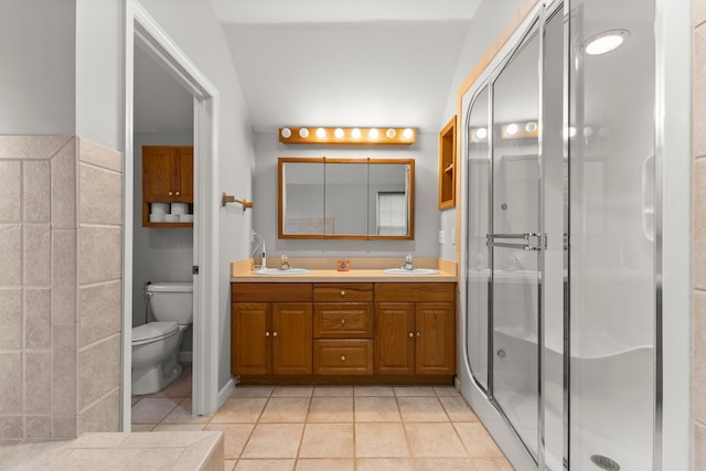 bathroom featuring toilet, a stall shower, double vanity, and a sink