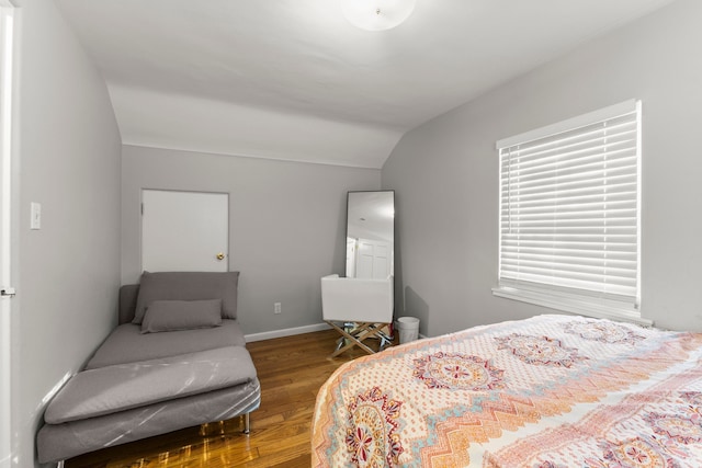 bedroom featuring lofted ceiling, baseboards, and wood finished floors