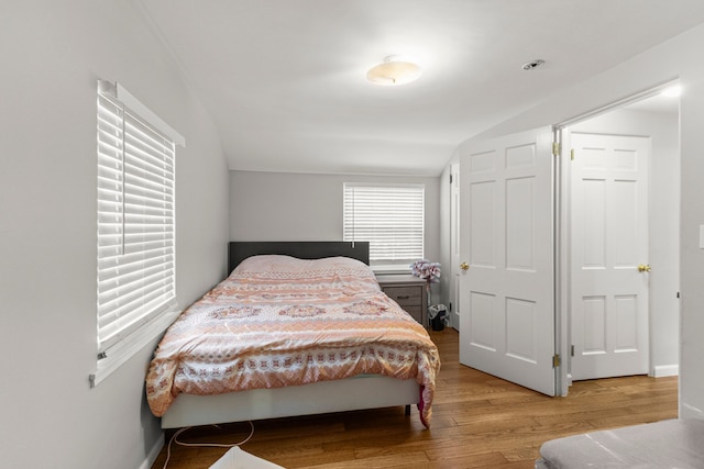 bedroom featuring lofted ceiling, baseboards, and wood finished floors