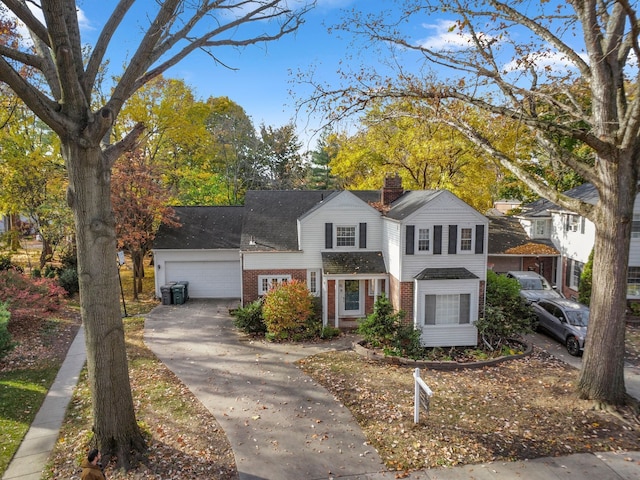 traditional-style house featuring a garage, brick siding, and a chimney