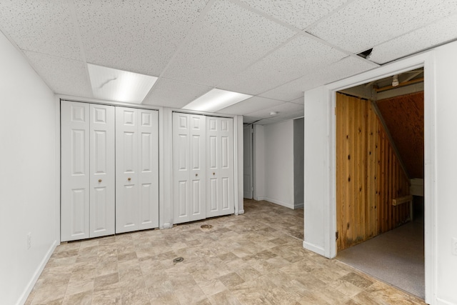 finished basement featuring a paneled ceiling and baseboards