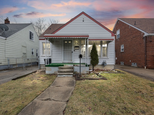 bungalow-style house with fence and a front lawn