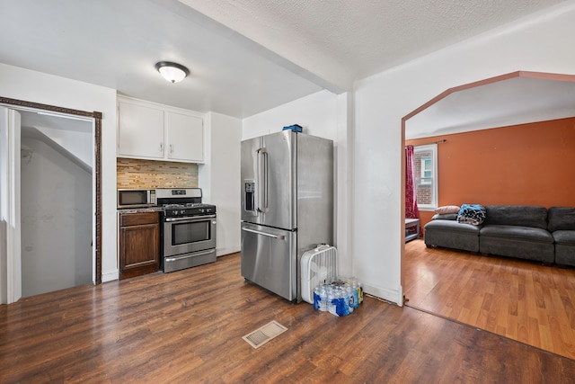 kitchen featuring visible vents, white cabinetry, appliances with stainless steel finishes, backsplash, and dark wood-style floors