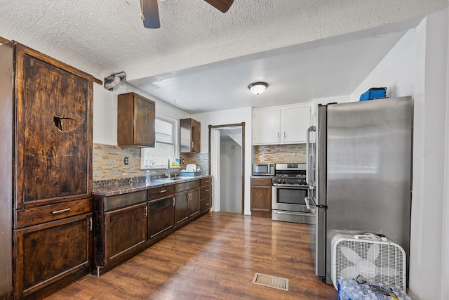 kitchen with dark wood-style floors, visible vents, backsplash, appliances with stainless steel finishes, and a sink