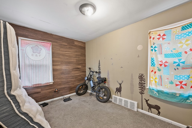 workout area with baseboards, visible vents, an accent wall, carpet flooring, and wood walls