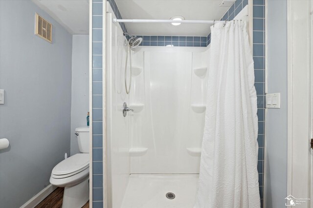 bathroom featuring visible vents, baseboards, toilet, wood finished floors, and a shower stall