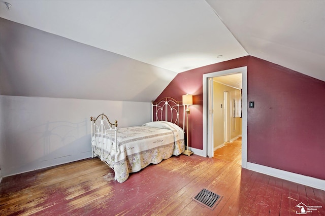 bedroom with vaulted ceiling, hardwood / wood-style flooring, visible vents, and baseboards