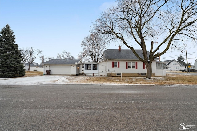 view of front facade featuring an attached garage, driveway, and a chimney