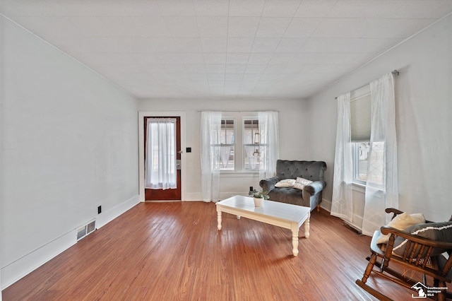 living area with visible vents, baseboards, and wood finished floors