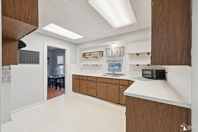 kitchen with black microwave, open shelves, a sink, and light countertops