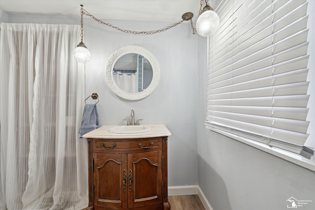 full bath with baseboards, wood finished floors, and vanity