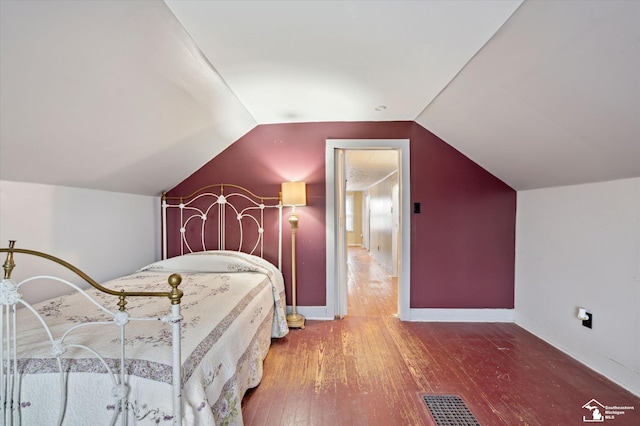 bedroom with baseboards, vaulted ceiling, visible vents, and hardwood / wood-style floors