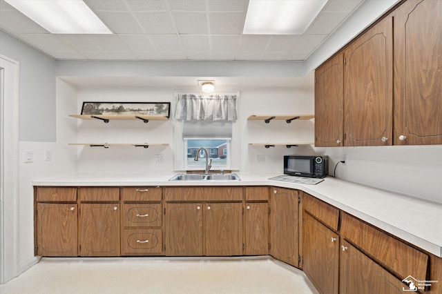 kitchen featuring brown cabinetry, black microwave, open shelves, and a sink