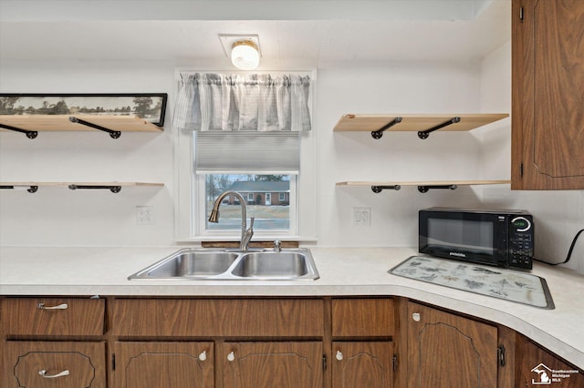 kitchen with black microwave, open shelves, a sink, and light countertops