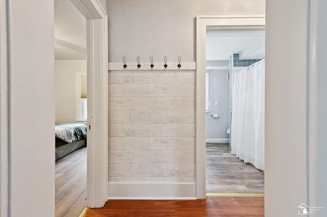 full bath with ensuite bath, a shower with shower curtain, and wood finished floors