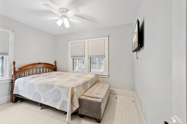 bedroom featuring wood-type flooring, multiple windows, and baseboards