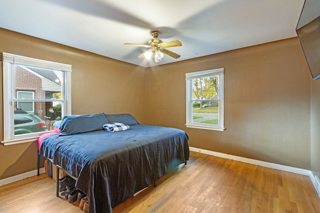 bedroom with ceiling fan, wood finished floors, and baseboards