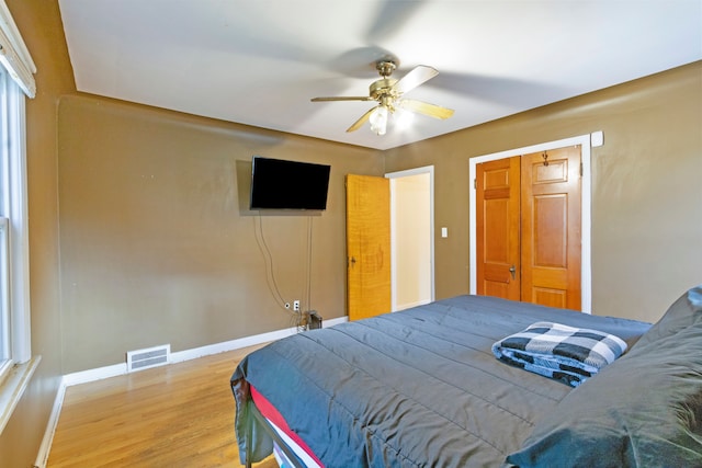 bedroom with light wood finished floors, visible vents, baseboards, and a closet