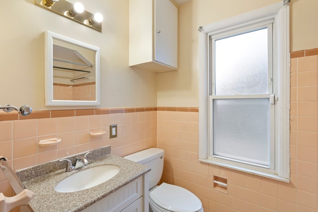 full bath featuring toilet, a wainscoted wall, tile walls, and vanity