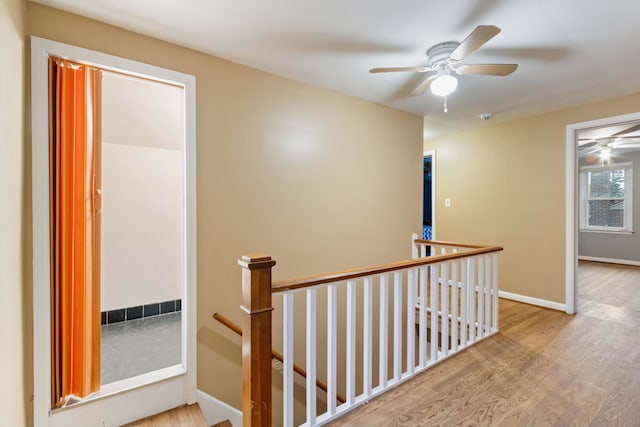 hallway featuring baseboards, an upstairs landing, and wood finished floors