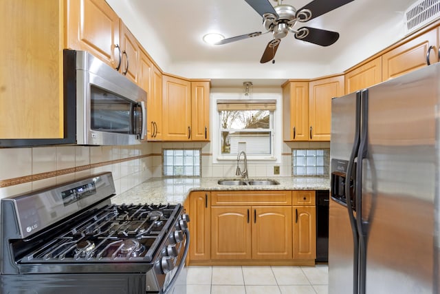 kitchen featuring visible vents, decorative backsplash, appliances with stainless steel finishes, light stone countertops, and a sink