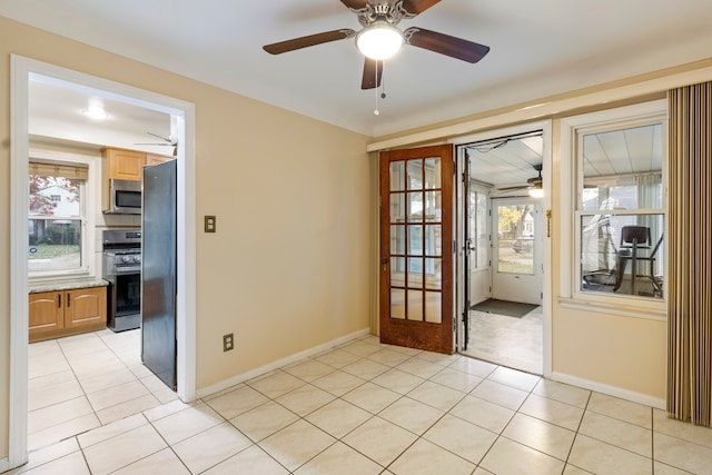 doorway with a ceiling fan, light tile patterned flooring, and baseboards