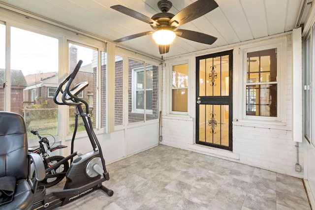 exercise room featuring a ceiling fan and brick wall