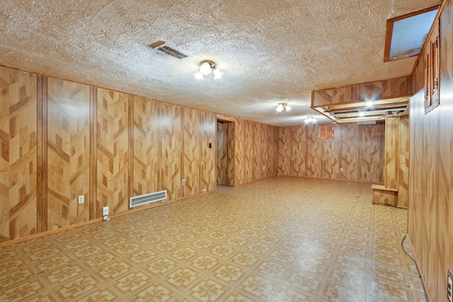 finished below grade area with light floors, visible vents, and wooden walls